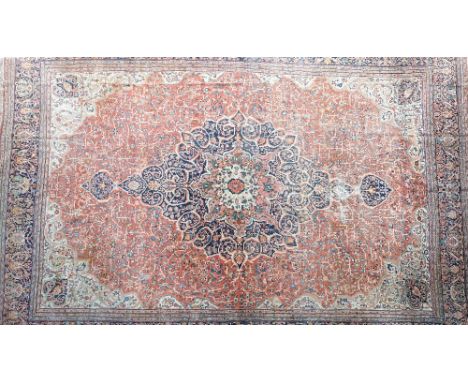 A large antique Kashan carpet, Persian, the madder field with a bold dark indigo, madder and sage medallion, ivory spandrels,