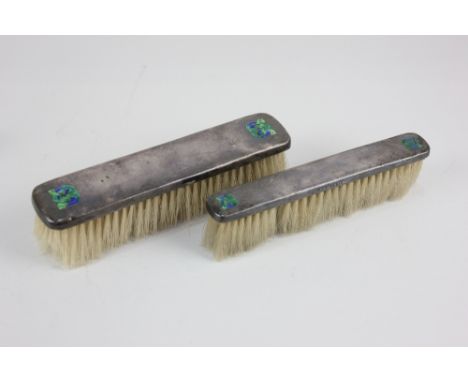 Archibald Knox, two Liberty &amp; Co silver clothes brushes, inlaid in enamel with Celtic knots, Birmingham 1905 and 1906, lo