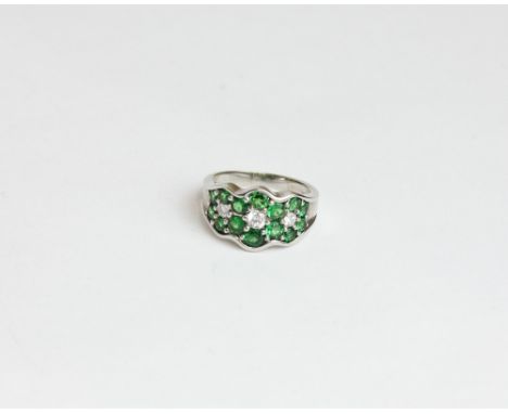 A diamond and green tsavorite ring set with three round diamonds and fourteen green garnets in 18ct white gold