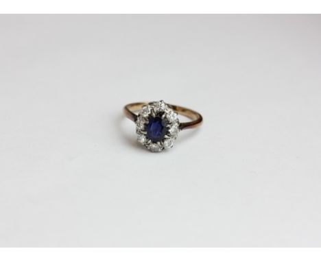 A sapphire and diamond cluster ring the oval cut stone claw set within a border of eight brilliant cuts