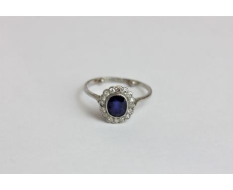A sapphire and diamond ring the oval cut stone rubover set within a border of eight cut diamonds