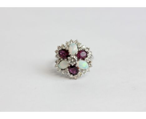 A ruby and opal cluster ring with three oval rubies and three opals in a diamond border in 18ct white gold 