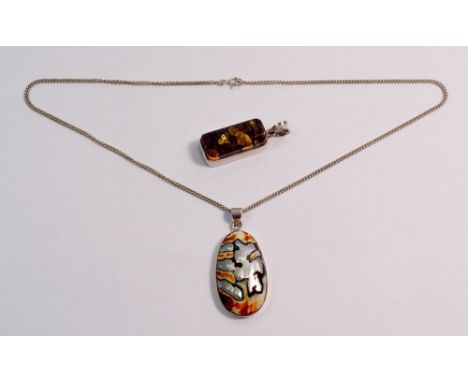 A silver shell pendant and a white metal pendant 