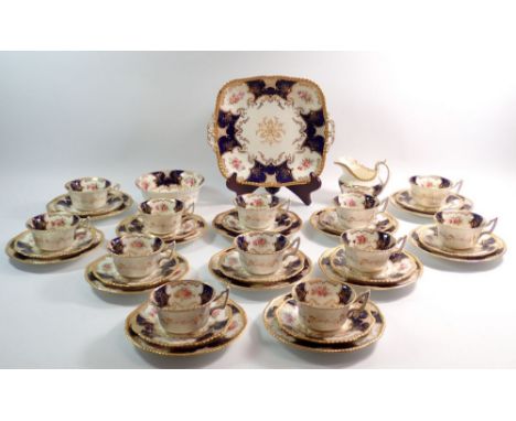 A Coalport tea service painted floral reserves on a blue and gilt ground comprising:- milk jug, sugar, cake plate, twelve tea