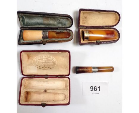 A yellow metal mounted amber cigar holder and two silver mounted cigar/cigarette holders - all cased 