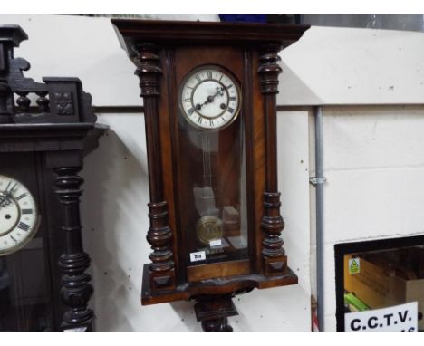 A Vienna-styled wall clock, walnut case with opening glazed door flanked by turned column decoration, white enamel two-piece 