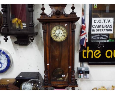 A Vienna-styled wall clock with glazed door, two-piece enamel and celluloid dial, walnut case with turned and carved decorati