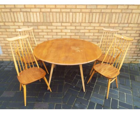 An Ercol light elm gate-leg drop-leaf dining table with two Ercol carver chairs and two matching standard chairs, with spindl