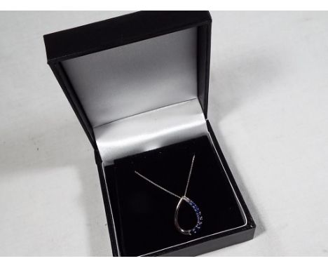 A lady's 9 carat white gold blue sapphire tear-drop pendant and chain, approx 1.3 gm (all in), unused surplus retail stock (N