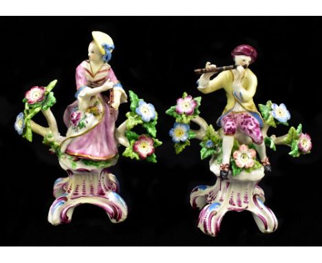 DERBY; a pair of 18th century figures of musicians, he playing the flute, she holding the flute, on puce heightened scrolling
