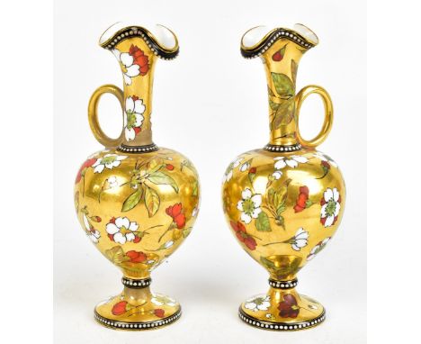 COALPORT; a pair of gilt and floral enamel decorated ewers with shaped rims and loop handles, both with green printed marks t