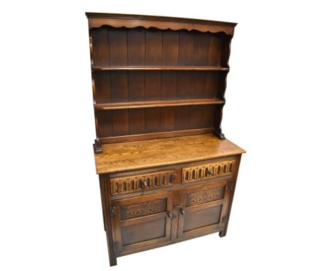 A reproduction oak dresser in the manner of Titchmarsh &amp; Goodwin, the panelled back with carved frieze and two shelves, t