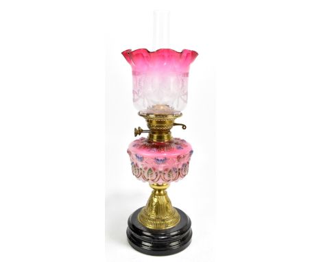 A Victorian oil lamp with moulded cranberry/milk glass reservoir, with brass mounts and cranberry and clear glass shade, over