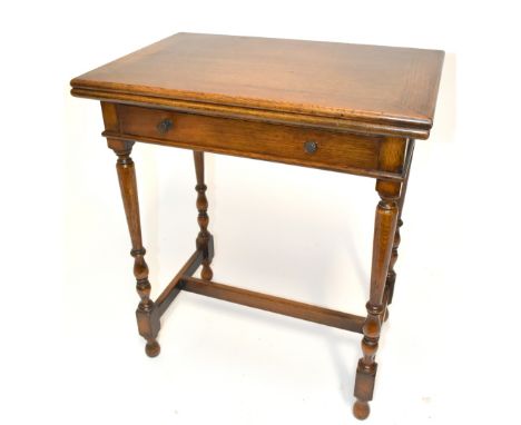 A small early 20th century oak foldover card table with frieze drawers on turned and stretchered supports, height 70cm, width