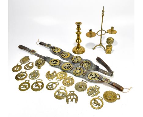 A group of horse brasses, some mounted on leather strap, a twin branch candelabrum, a single candlestick, a lion head door kn
