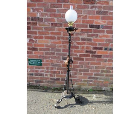 A WROUGHT IRON FLOOR STANDING OIL LAMP, having scrollwork decorations, hammered copper floral embellishment and a twist lock 
