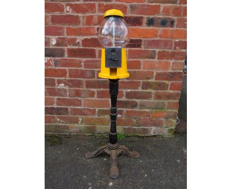 A VINTAGE AMERICAN GUMBALL MACHINE ON CAST IRON BASE, with yellow painted alloy body and glass globe, 1p or 1 cent vend, H 10