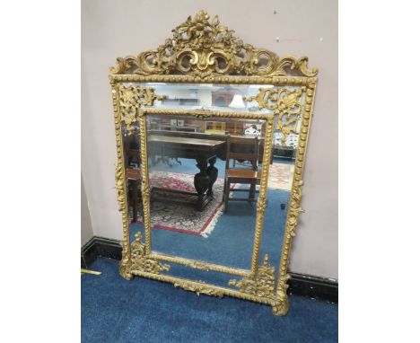 AN EARLY 19TH CENTURY GILT AND COMPOSITION WALL MIRROR, the scrolling Rococo style surmount above two bevelled plates, with s