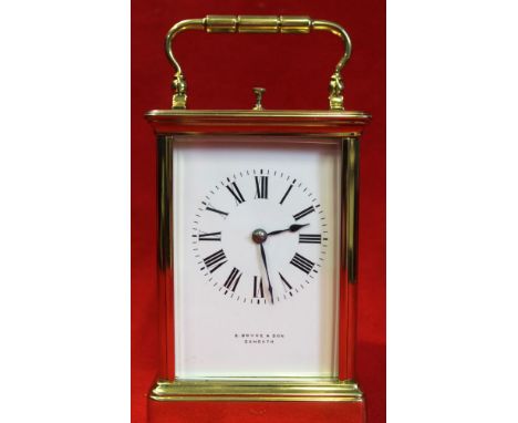 A brass frame carriage clock with hinged bale handle, white enamel face with Roman numerals, inscribed "E. Boyce &amp; Son Ex