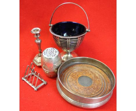 A silver bottle coaster, candlestick, barrel pepper, mini toast rack, and pierced basket