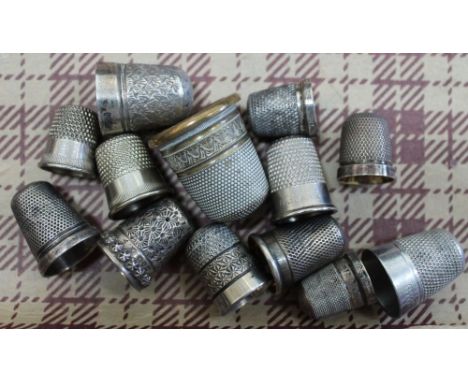 A selection of thimbles, some silver, some white metal, includes a thimble tape measure