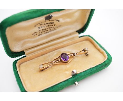 An early 20th Century yellow-metal amethyst and pearl geometric openwork bar brooch, having a central millegrain set amethyst