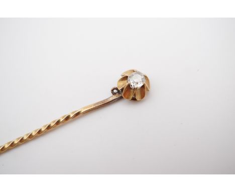 An antique diamond solitaire stick pin, the cushion-cut diamond of approximately .16ct, claw set in a cusped, flower-head fra