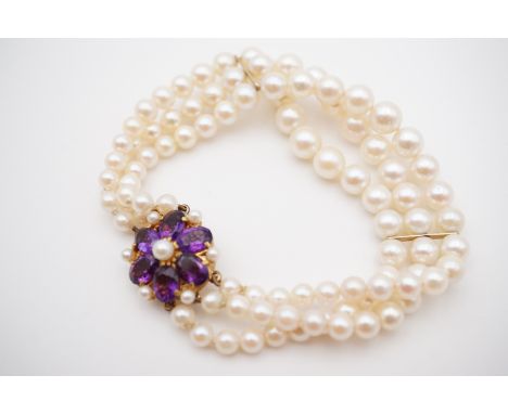A yellow-metal, pearl and amethyst bracelet, comprising three strands of graded pearls fastening with an amethyst and pearl f