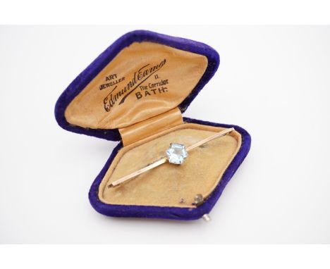 An Art Deco yellow-metal and aquamarine bar brooch, the hexagonal cut aquamarine being crown set on a planar bar, 2.4g, in ge