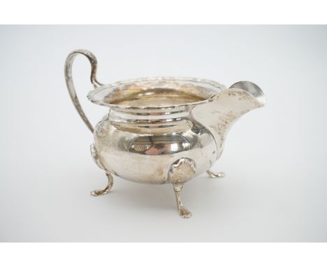 A 1920s silver sugar bowl and cream jug, each of oblate form with a Chippendale style rim flange and bifurcated whiplash hand