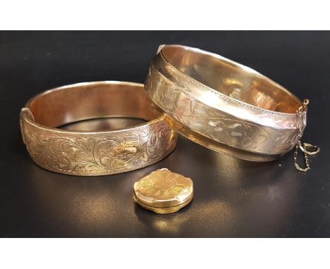 TWO GOLD PLATED HINGED BANGLESboth with engraved scroll decoration, one with safety chain; together with a gold plated locket