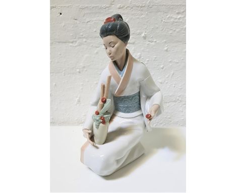 LARGE NAO PORCELAIN FIGURINEof a Geisha kneeling with a vase of flowering bamboo, 34.5cm high 