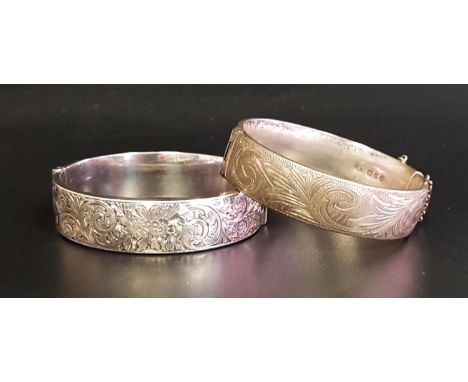 TWO SILVER HINGED BANGLESboth with engraved scroll decoration, one with safety chain, London 1959 and Birmingham 1951 respect
