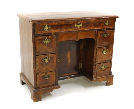 A George I and later kneehole walnut desk. the crossbanded rectangular top above frieze drawer, with three further drawers to