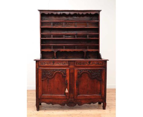 A French carved chestnut dresser,18th to 19th century, with a boarded plate rack above a foliate-decorated base, comprising t