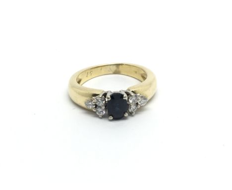 An 18carat gold ring set with a blue sapphire flanked by brilliant cut diamonds Ring size I.