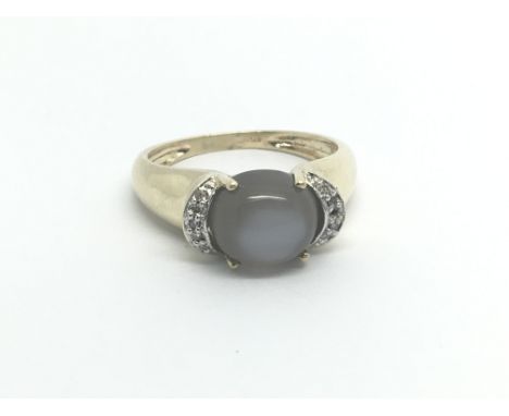 A 9carat gold ring set with moon stone flanked by chip diamonds ring size N-O