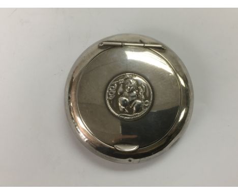 A circular silver tobacco box, the lid inset with a cherub, approx diameter 8.5cm.