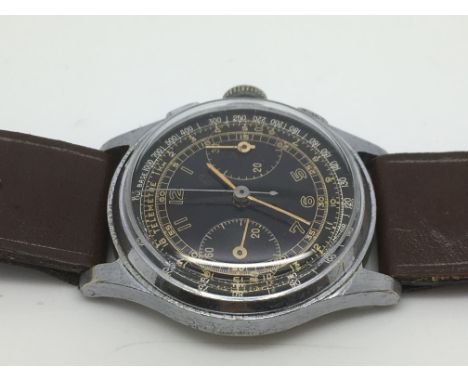 A gents chronograph watch with military style black dial and a period perforated brown leather strap, circa 1950s/60s. Seen w