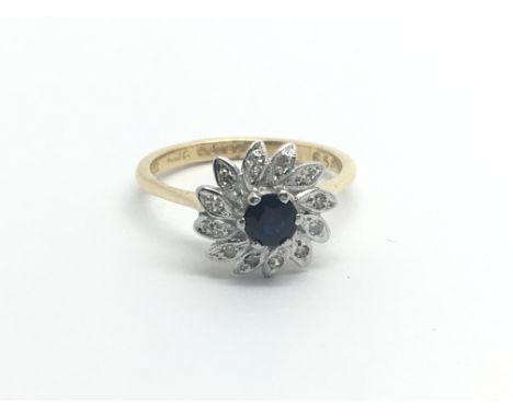 An 18carat gold ring set with a central sapphire and a cluster of diamonds ring size L-M