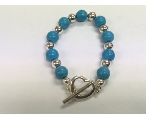 A silver and turquoise bracelet with a heart shaped clasp.