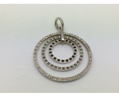 A silver and stone set modern pendant of circular form.