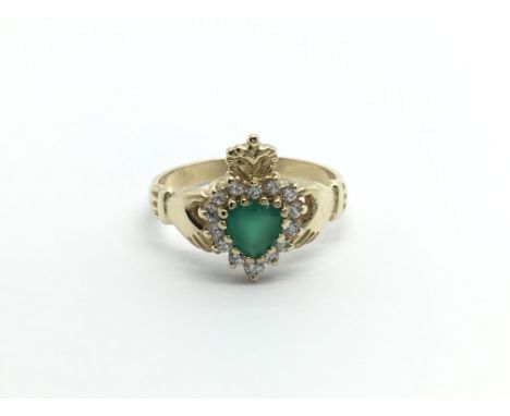 An unmarked gold ring of Irish Claddagh type set with green and CZ stones ring size K.