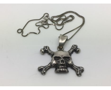 A sterling silver skull and crossbones pendant on chain.