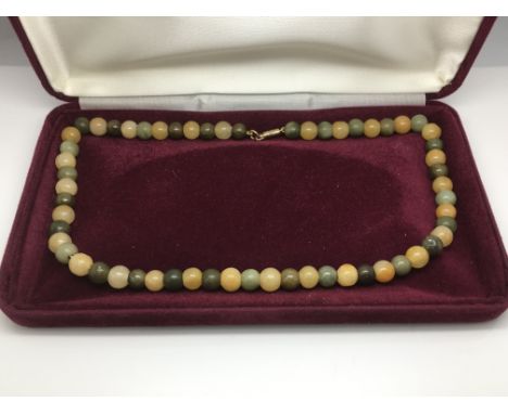 A multi coloured jade necklace with a 9ct gold clasp.