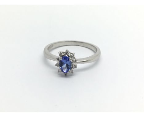 A Platinum ring set with a Ceylon sapphire flanked by an oval of diamonds ring size P.