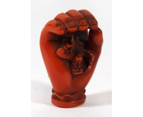 A Japanese simulated amber netsuke, 20th Century Modelled depicting Hanuman, seated within an openwork hand, signed to base, 