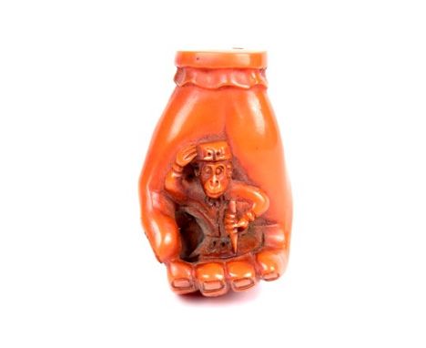 A Japanese simulated amber netsuke, 20th Century Modelled depicting Hanuman, seated within an openwork hand, signed to base, 
