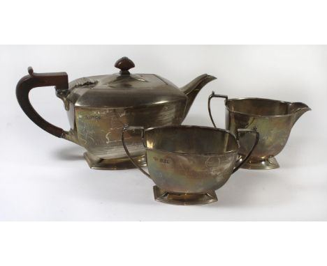 An Elizabeth II silver three piece tea serviceComprising teapot with hinged lid and applied wooden handle and lid finial, tog