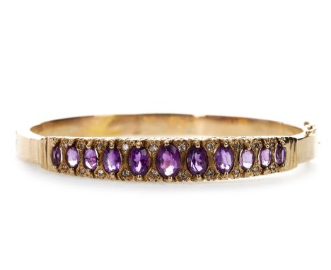 PURPLE GEM AND DIAMOND BANGLE, with graduated oval purple gems interspaced by pairs of round brilliant cut diamonds totalling
